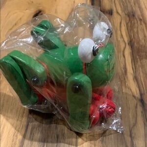 World a market wooden green frog on red wheels toy